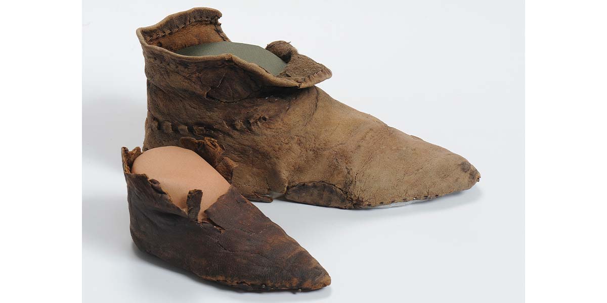 Deux chaussures de l'An mil en cuir. Une chaussure d'adulte. Une chaussure d'enfant.